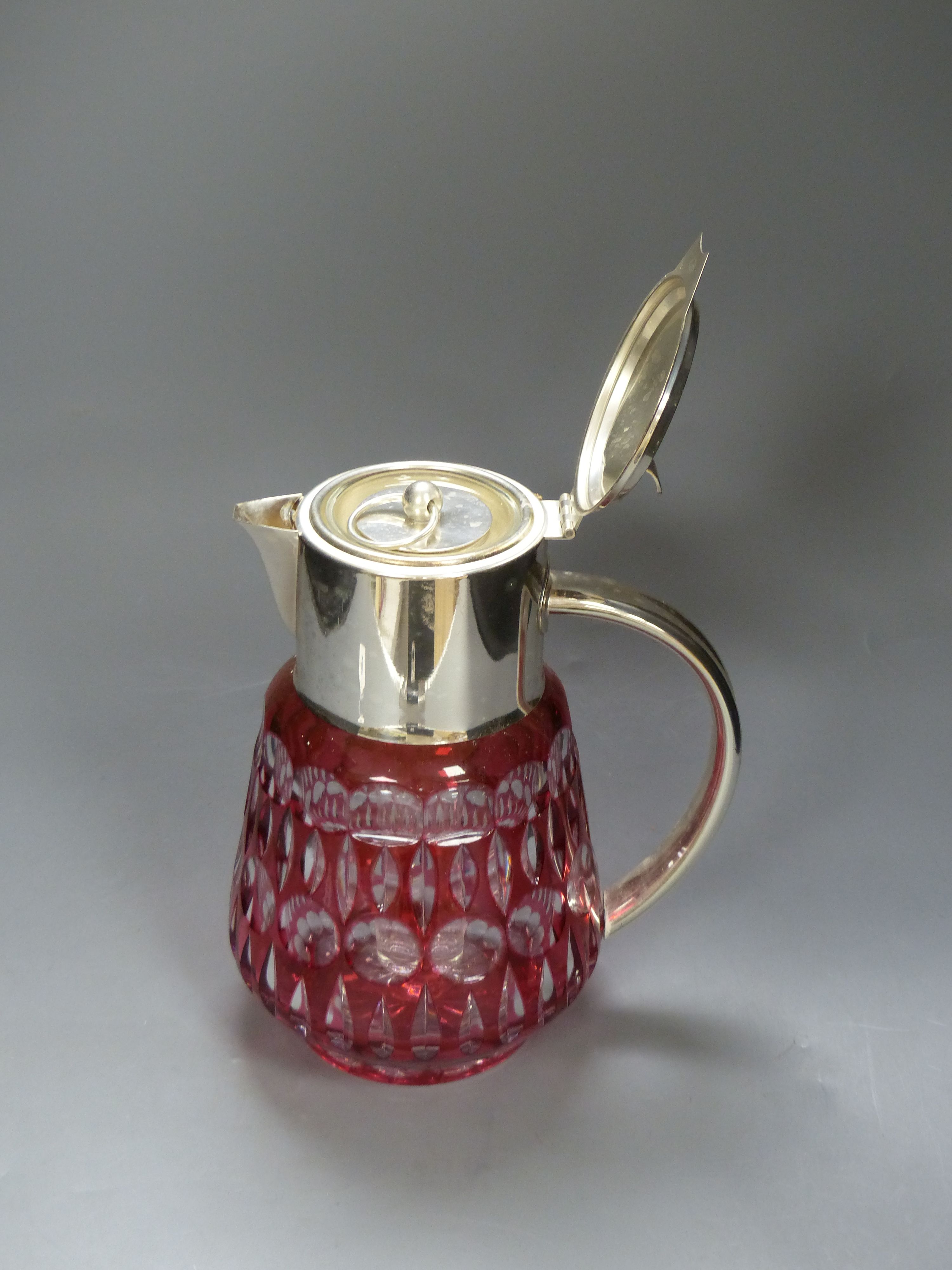 A large cranberry overlay cut glass lemonade jug with plated cover and handle, with removable ice tube, height 27cm